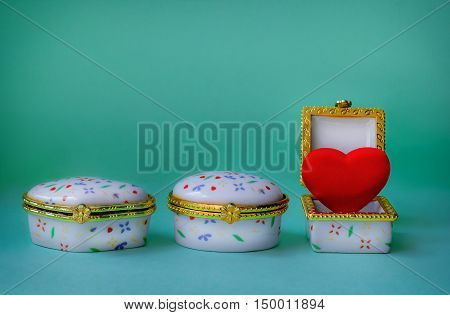 Jewelry boxes with one having a red heart inside on blue background
