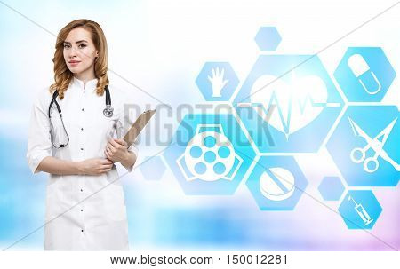 Gourgeous woman doctor with red hair is holding her clippad and standing near health icons. Concept of medical establishment employee. Double exposure