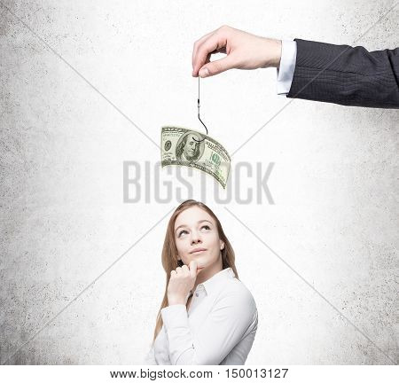 Dreamy girl in white shirt considering if she should take a bait proposed by businessman. Concept of bribing