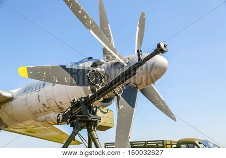 Retro gun on the tripod and optical sight, against the backdrop of the aircraft propellers, close-up. Machine gun outdoors.