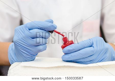 Female Hand With Gloves Opens A Bottle Of Red Lacquer