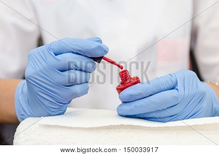 Female Hand With Gloves Opens A Bottle Of Red Lacquer