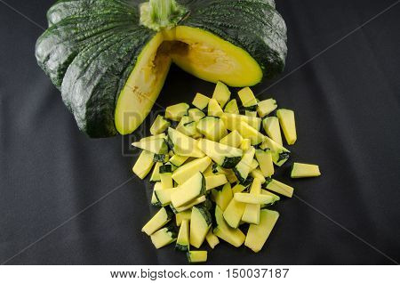 Sliced raw yellow pumpkin on black background. Sliced yellow pumpkin and green pumpkin for use as cooking ingredients