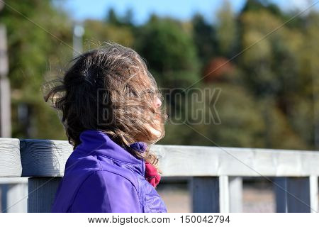 Woman daydreaming. Wind blowing her hair snd cover face.