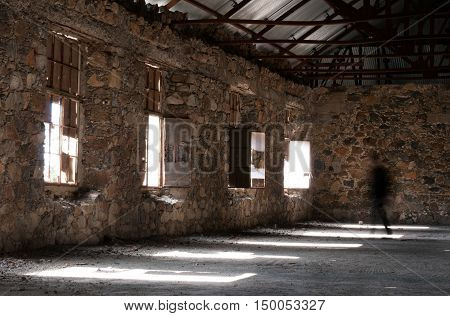 Empty abandoned creepy hotel room with sun lights entering the windows and a ghost walking