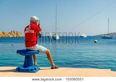 Sailing race referee watching at the yachts at anchorage in beautiful Sardinian bay. Italy.