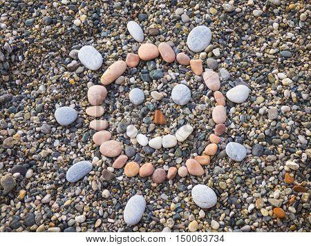 Stone sun face with pebbles on beach