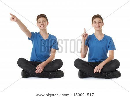 Cute teenager boy poinitng up side in blue T-shirt and lotus posture over white isolated background