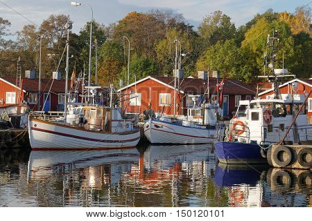 Small fishing boats in the harbor reflecting in the water a perfect sunny windless morning