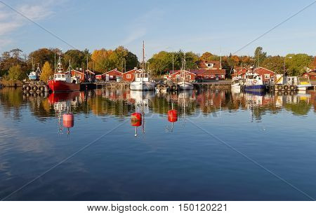 Small fishing boats in the harbor reflecting in the water a perfect sunny windless morning