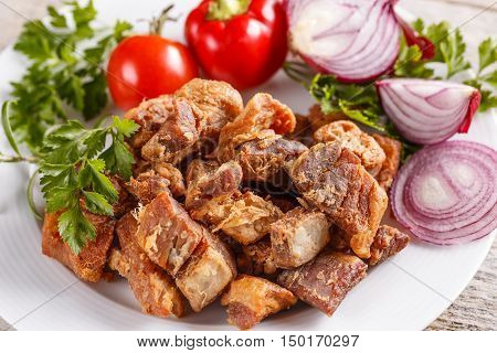 Plate of salty pork greaves, studio shot