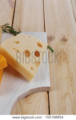 various types of fresh raw aged delicatessen cheese on white plate over light wooden table cheddar edam swiss