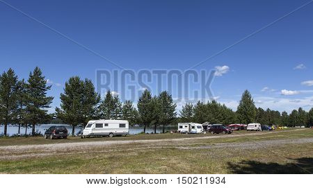 MEDELPAD, SWEDEN ON JULY 09. View of a campsite, car, campers and caravan on July 09, 2016 by Holmsjon, Sweden. Sunny summer day. Pine forest and a lake. Editorial use.