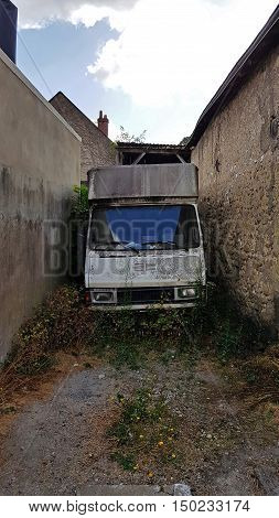 Old destroyed transport van standing between buildings.