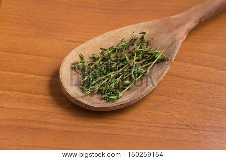 Fresh Thyme into a spoon over a wooden table