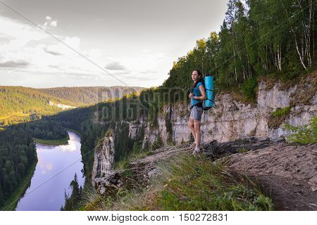 Hiker with backpack standing on a rock and looking to the beautiful landscape, meeting sunrise, Russia, Ural