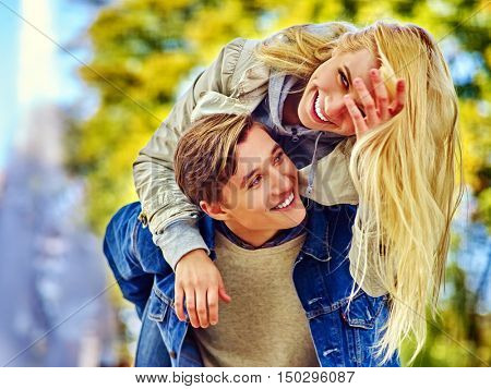 Young couple hugging and flirting in fall park . Beautiful happy blond girl with long hair hugging her favorite guy in fall park.
