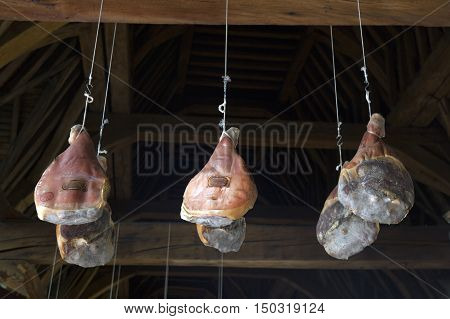 hams hang from very old wooden beams in Ghent Meat Hall