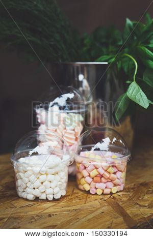 Desserts choice. Marshmallow chewing candies in glass jars on counter bar for sale. Traditional american sweets for sale, closeup, vertical