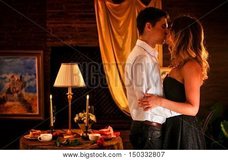 Luxary home interior. Couple in love dancing and kissing into luxary restaraunt. Romantic evening interior for loving couple. A lot of pictures in room.