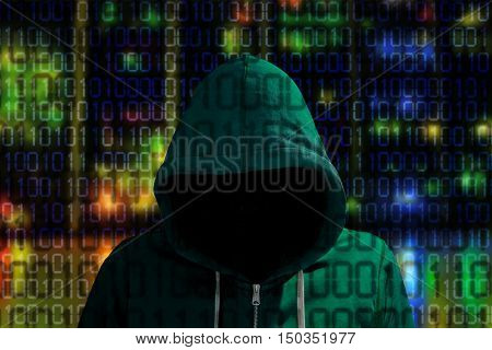Hacker in a green hoody standing in front of a colored server background with binary streams cybersecurity concept