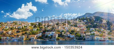 Panoramic shot of the Harbour at Symi Greece with a traditional fishing boat in the foreground. Greece Europe.