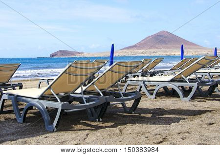 Two sunbeds on a beautiful beach de MedanoTenerife Canary Islands. Concept for vacations or tourism
