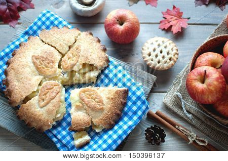 Sliced apple pie with fruit ingredients and cinammon sticks on one side