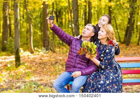 family, pet, season, technology and people concept - happy family with labrador retriever dog taking selfie by smartphone in autumnl park