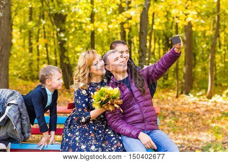 family, pet, season, technology and people concept - happy family with labrador retriever dog taking selfie by smartphone in autumnl park