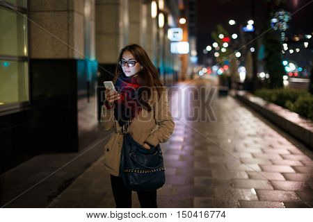 Attractive young woman looking at the phone at night