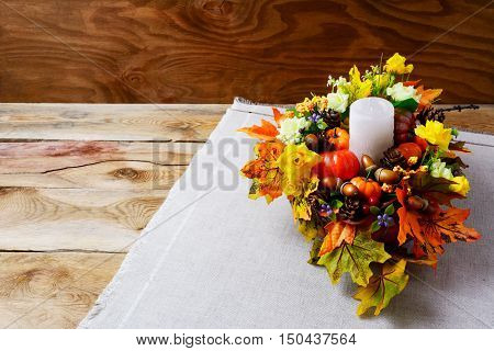 Thanksgiving centerpiece with candle and artificial fall leaves. Thanksgiving background with fall decor. Fall background. Copy space.