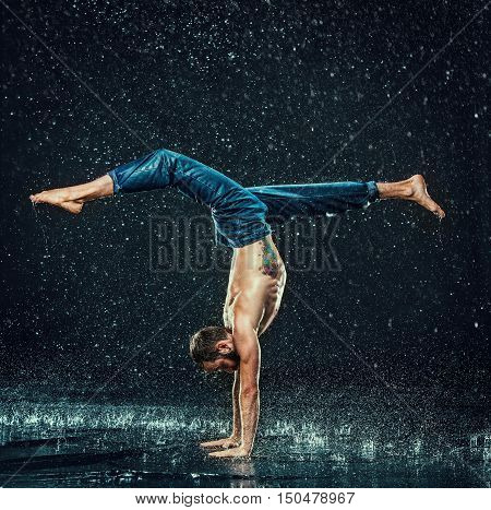 The male break dancer in water on dark background.