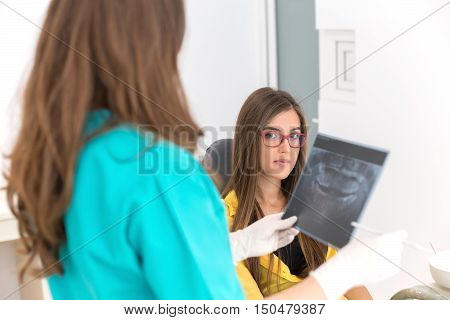 Female dentist showing her patient x-ray radiography, in the Dental Clinc