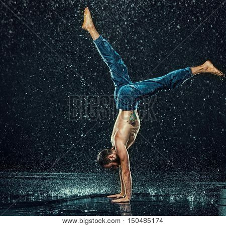 The male break dancer in water on dark background.