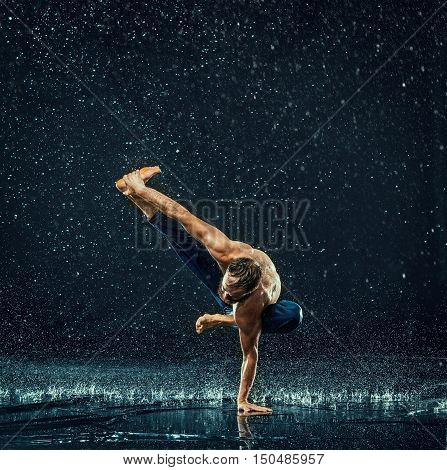 The male break dancer in water on dark background.