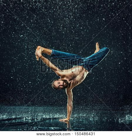 The male break dancer in water on dark background.