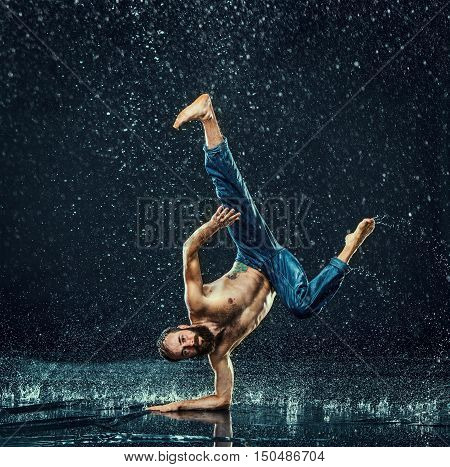 The male break dancer in water on dark background.
