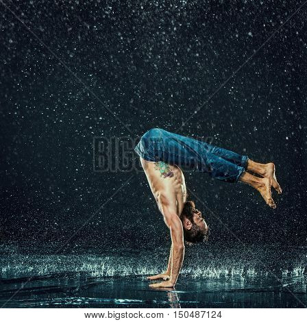The male break dancer in water on dark background.