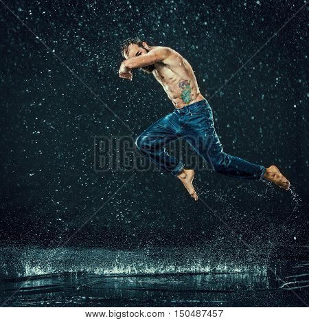 The male break dancer in water on dark background.