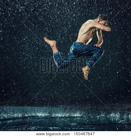The male break dancer in water on dark background.