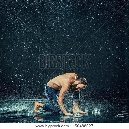 The male break dancer in water on dark background.