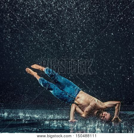 The male break dancer in water on dark background.