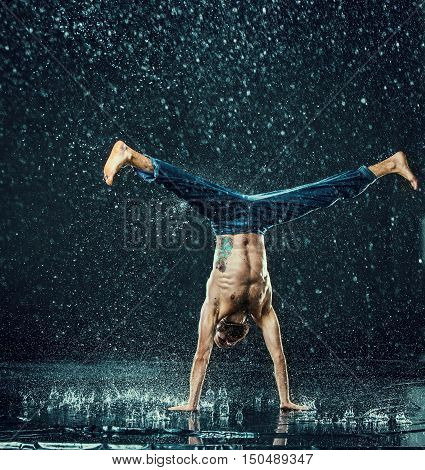 The male break dancer in water on dark background.