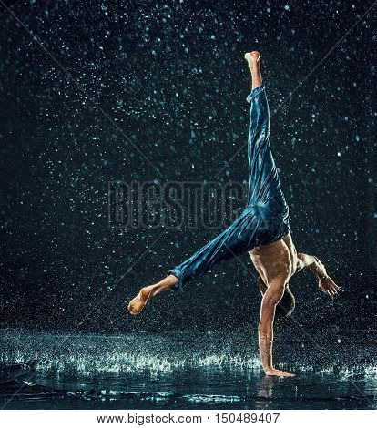 The male break dancer in water on dark background.