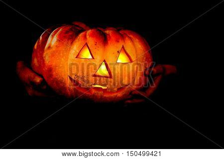 Hands Boy in halloween masquerade costume ih light from pumpkin head. Close-up