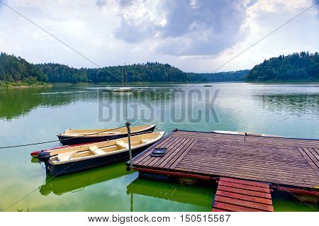Boats tied to floating dock in Pilchowice Lake Poland on sunny day.