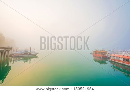 SUN MOON LAKETAIWAN - MARCH 21: Fog with many boats parking at the pier while sunrise on MARCH 21 2015 at Sun Moon Lake Taiwan. Sun Moon Lake is the largest body of water in Taiwan with nataral place.