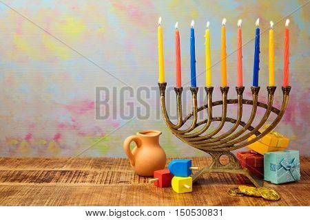 Jewish holiday Hanukkah celebration with menorah dreidel gifts and oil jug on wooden table