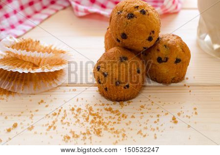 Little chocolate muffins with paper cupcake holder and brown sugar on wooden background